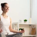 Frau beim Meditieren und Atemübung im Wohnzimmer.