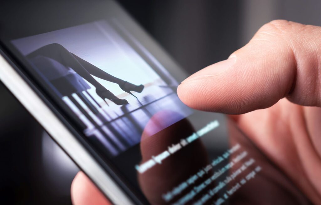 Escort Munich: Finger scrollt über Smartphone mit Beinsilhouette